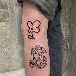 Get an edgy yet beautiful tattoo by Charlie Macarthur, featuring a fierce tiger and delicate flower design.