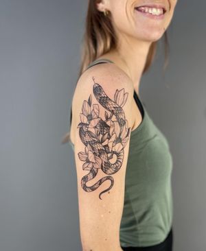 Beautiful illustrative tattoo featuring a snake entwined with a flower, created by the talented artist Paula.