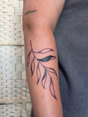 Beautiful tattoo featuring a detailed branch with delicate leaves, created by the talented artist Claudia Vicente.