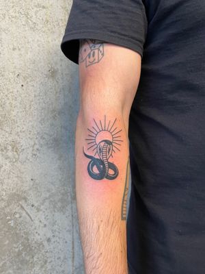 Traditional tattoo design featuring a vibrant sun and menacing snake, done by renowned artist Rich Sinner.