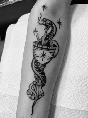 Unique dotwork and traditional tattoo design featuring a mystical snake entwined around a chalice and grail, etched by artist Claudia Vicente.