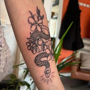Get a unique illustrative tattoo of a snake and flower by renowned artist Claudia Vicente. Express your creativity and beauty with this stunning design.