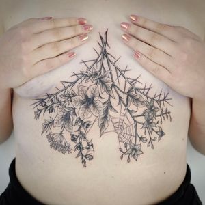 Beautifully designed tattoo featuring flowers, thorns, plants, and spider web by Paula. Perfect for nature lovers!