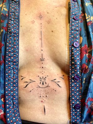 Elegant ornamental pattern tattoo on the stomach by Charlotte Pokes, expert in intricate designs.