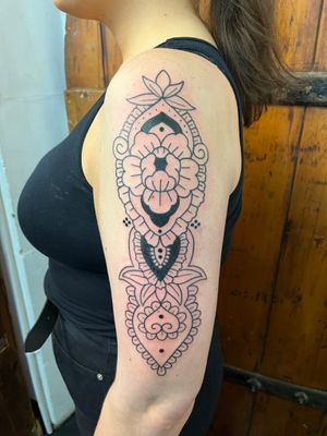 Experience the intricate beauty of this geometric, ornamental tattoo design showcasing a mesmerizing fusion of flowers and mandalas created by the talented artist Claudia Vicente.