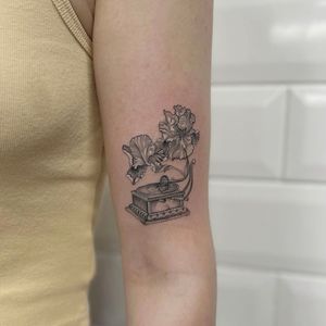 Beautifully detailed tattoo featuring a delicate flower and vintage gramophone, expertly executed by Holly Valley in fine line micro realism style.