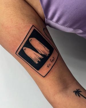 Illustrative tattoo featuring a card, polaroid, sheet, and ghost; uniquely haunting design with no feet. Created by the talented artist Miss Vampira.