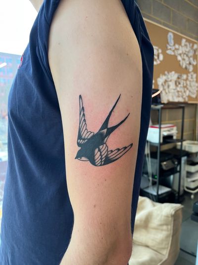 Get inked with a classic swallow bird tattoo in illustrative style by Dave Norman. Bold and timeless design.