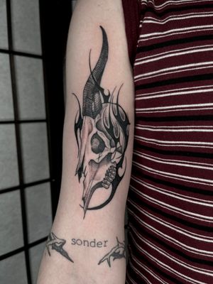 Unique blackwork tattoo by artist Dominga Longo combining skull imagery with tribal elements for a bold and edgy look.