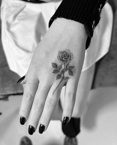 Experience traditional beauty with this stunning rose tattoo by Ion Caraman, perfectly placed on your hand.