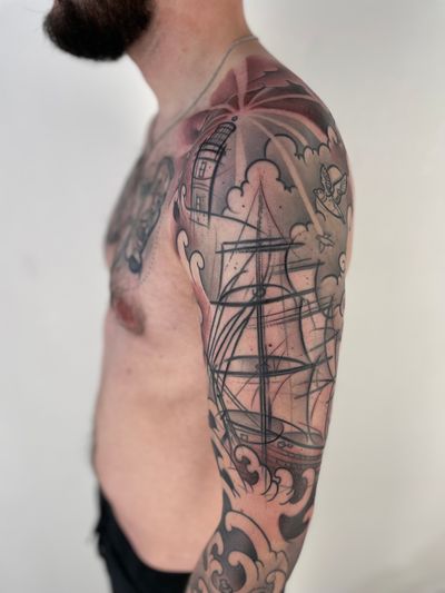 Sail the waves with this stunning tattoo by Hannah Keuls, featuring a detailed lighthouse and ship design.