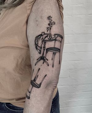 Capture the beauty of everyday objects with this stunning illustrative tattoo of a table, chair, and vase by the talented artist Ludo Matmut.