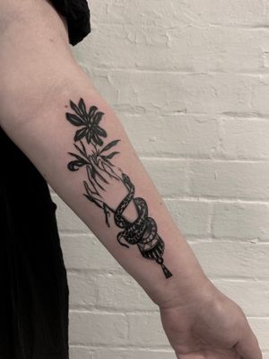 Get inked with a stunning traditional tattoo featuring a snake, flower, and hands by the talented artist Ludo Matmut.
