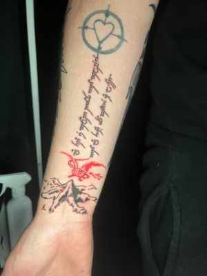 Experience the mystique of Middle Earth with this small lettering and illustrative tattoo featuring a dragon in elvish style by the talented artist Ben Twentyman.