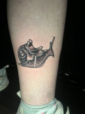 Admire the intricately detailed black and gray illustration of a snail and saddle by tattoo artist Ben Twentyman.