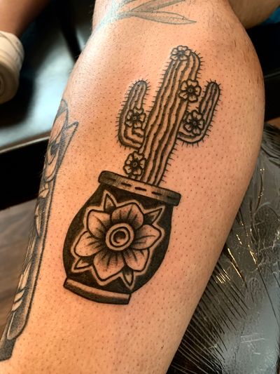 Get inked with a stunning illustrative tattoo of a cactus in a vase by the talented artist Angel Face.
