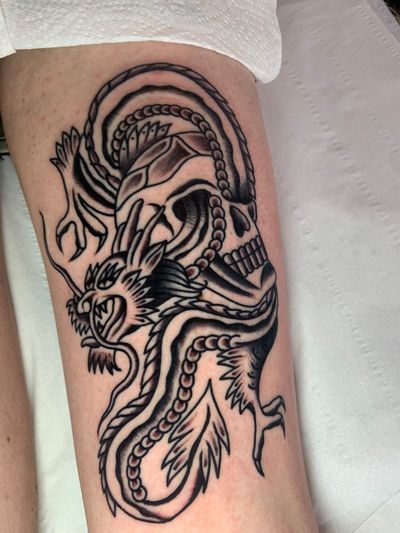 Get a fierce and bold traditional tattoo of a dragon and skull by the talented artist Angel Face. Embrace the mystique and power of this dark yet beautiful design.