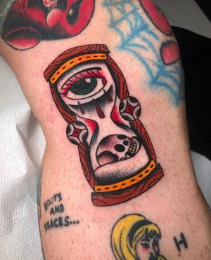 Experience the passage of time with this traditional tattoo featuring a skull, hourglass, and eye by Angel Face.