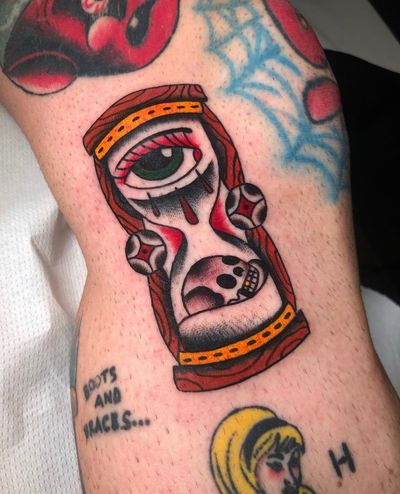 Experience the passage of time with this traditional tattoo featuring a skull, hourglass, and eye by Angel Face.