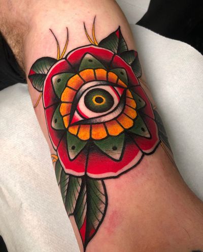 Experience the beauty of a traditional tattoo featuring a stunning Tudor rose and captivating eye, by Angel Face.
