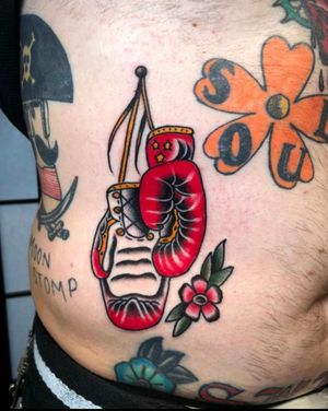 Get a traditional tattoo of boxing gloves and a box with intricate details by Angel Face. Perfect for boxing enthusiasts!
