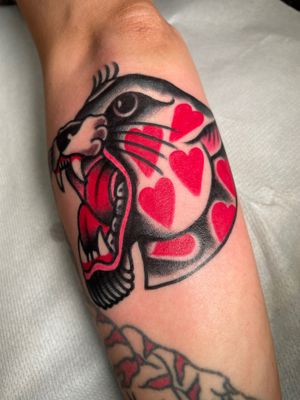 Get a fierce yet loving traditional tattoo of a panther and heart, designed by Angel Face.