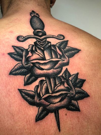 Stunning black and gray tattoo featuring a rose intertwined with a sword, done by Angel Face in a traditional style.