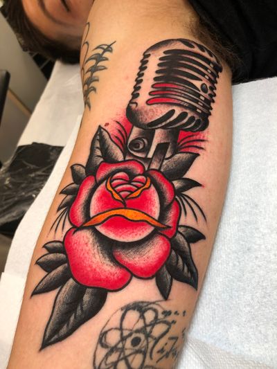 Get inked with a stunning illustrative design featuring a beautiful peony flower intertwined with a classic microphone, done by the talented artist Angel Face.