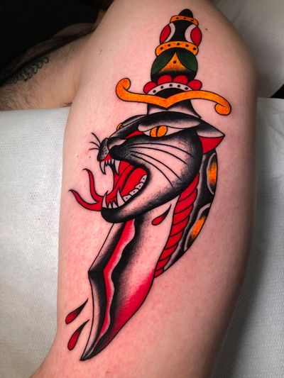Get a fierce and classic traditional tattoo featuring a panther and dagger, expertly inked by artist Angel Face.