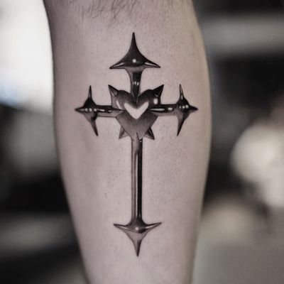 Gloria Gu's black and gray illustrative tattoo features a chrome heart and cross design, giving it a metal finish.