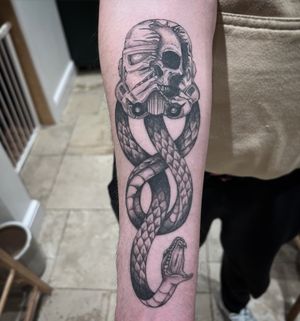 Get the perfect blend of rebellion and fandom with this unique tattoo by Hannah Senoj, featuring a snake, skull, and stormtrooper from Star Wars.