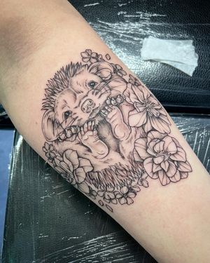 Beautiful illustrative tattoo featuring a delicate flower and a cute hedgehog, created by talented artist Hannah Senoj.