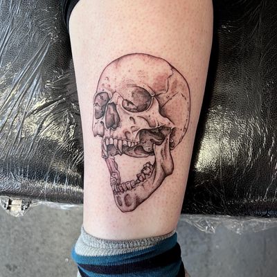 Illustrative tattoo by Hannah Senoj featuring a spooky skull with vampire fangs. Perfect for fans of dark and mysterious vibes.