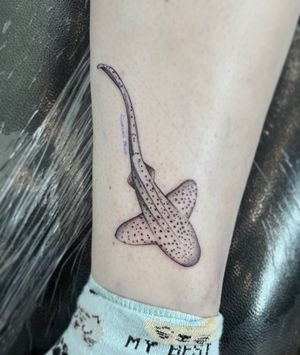 Witness the beauty of nature with this stunning illustrative tattoo featuring a graceful leopard shark, expertly brought to life in stunning realism by artist Hannah Senoj.
