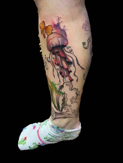 Swim with the fishes and jellyfish in this vibrant and artistic illustrative tattoo design. Dive into a world of color and creativity with this unique piece by talented artist Eve inksane.