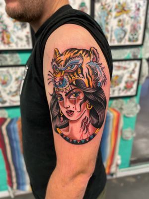 Capture the fierce beauty and strength of a tiger alongside the grace and elegance of a woman with this traditional style tattoo by River Tatts.