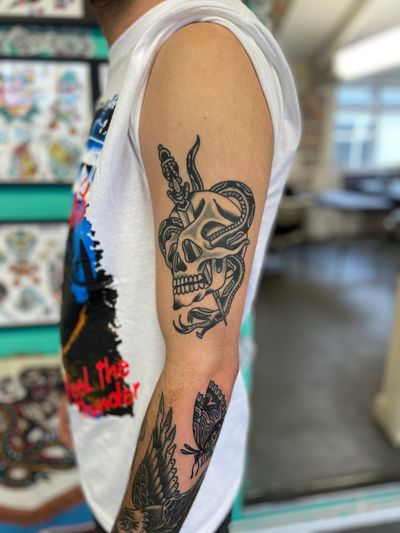 Get a bold and classic look with this traditional skull and dagger tattoo by River Tatts. Perfect for those who dare to be different.