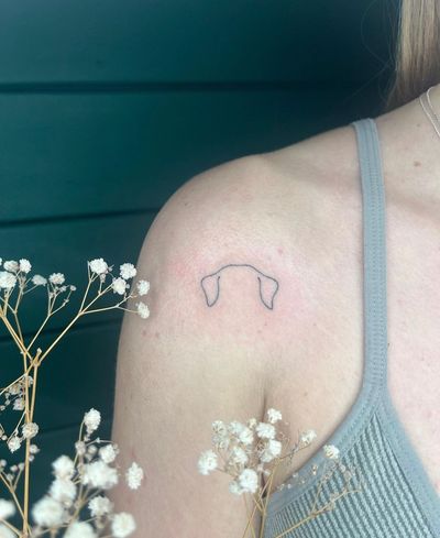 Fine line tattoo of dog ears, done by Abbie Lou. A simple and elegant design for dog lovers.