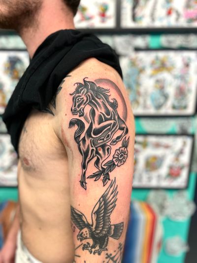 Artist River Tatts creates a stunning traditional tattoo design featuring a majestic horse and delicate flower motif. Perfect for lovers of classic tattoo art.