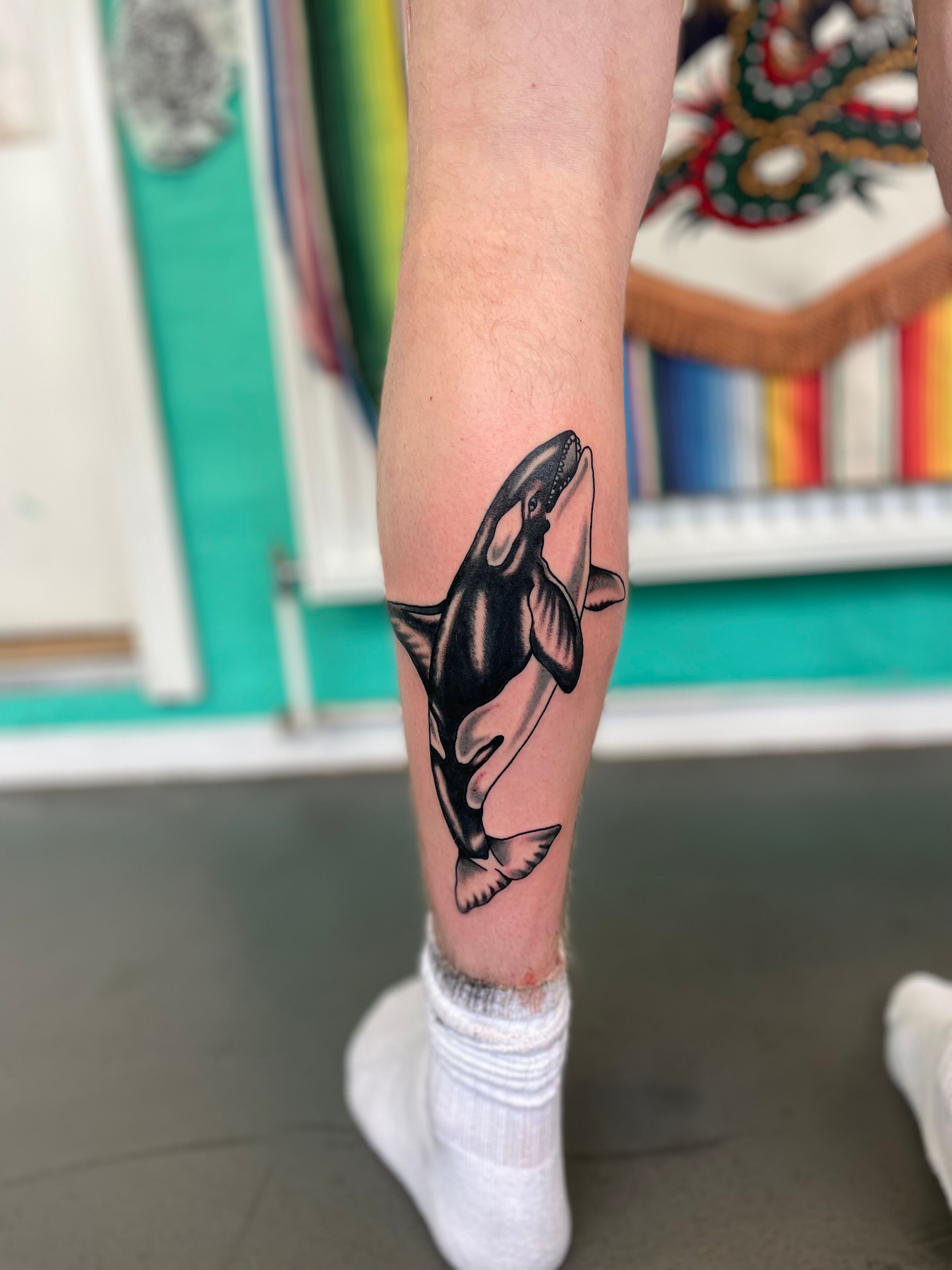 Minimalsitic orca tattoo located on the wrist.