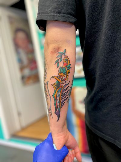 Get a bold traditional dagger tattoo design from the skilled artist River Tatts. Stand out with this timeless symbol of protection and bravery.