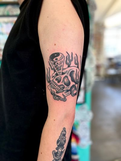 Embrace duality with this bold and striking traditional tattoo by River Tatts, featuring a skull intertwined with a ying yang symbol.
