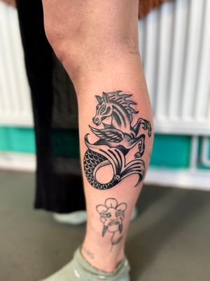 Experience the enchantment of this traditional style tattoo featuring a horse, seahorse, and mermaid, skillfully done by River Tatts.