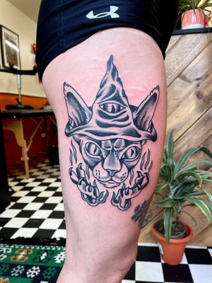 Get bewitched with this traditional tattoo featuring a wise cat wizard, done by the talented artist River Tatts.