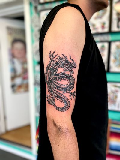 Get inked with a fierce and timeless dragon design done in classic traditional style by the talented artist River Tatts. Stand out with this bold and powerful tattoo!
