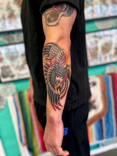 A stunning traditional eagle tattoo, expertly done by River Tatts. Bold lines and vibrant colors bring this majestic bird to life.