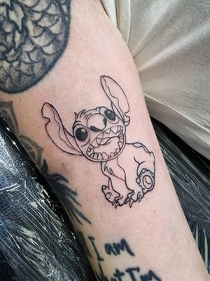 Get a unique, fine line tattoo of Disney's beloved character Stitch, beautifully designed by artist Iva M.