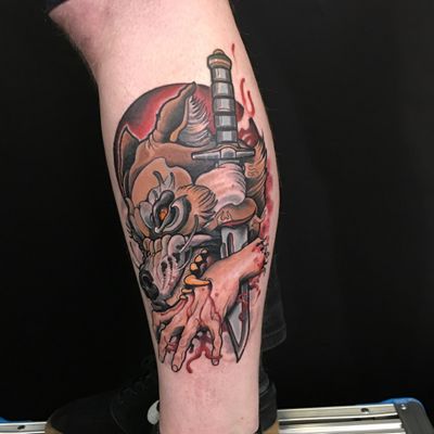 A striking neo-traditional tattoo by Jethro Wood featuring a wolf, knife, and hand motifs for a dark and daring design.