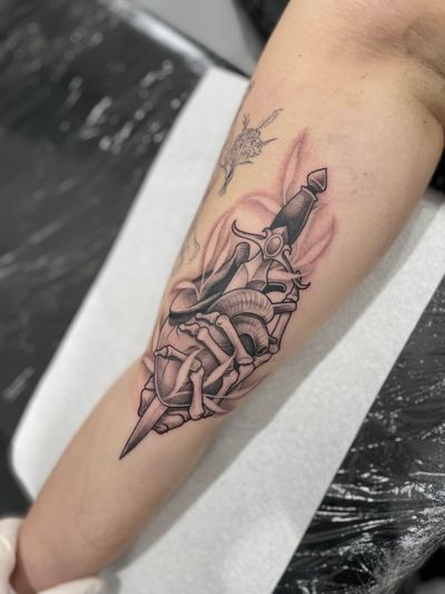Heart and dagger held by a skeleton hand