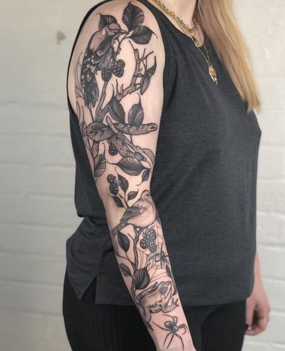 Admire the intricate details of this illustrative tattoo by Claudia Smith, featuring a snake, bird, spider, flower, branch, and berry motif.